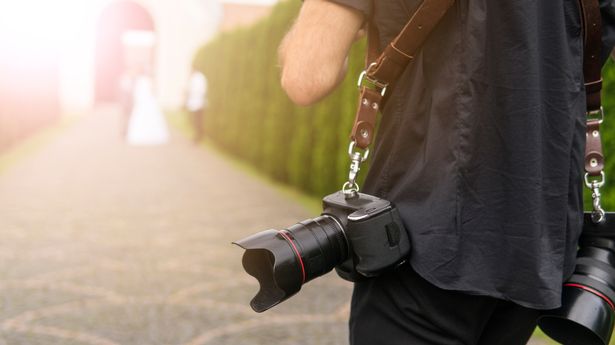 1_Professional-wedding-photographer-takes-pictures-of-the-bride-and-groom-in-garden-the-photographer